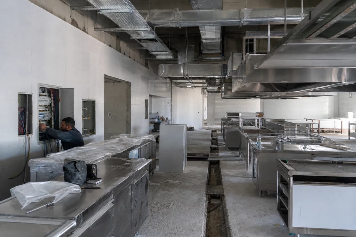 Restaurant fit-out Syria commercial kitchen with open MEP ducts, extract framing, and drainage works before finishes